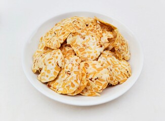 Close-up of tempeh chips in a white plate on a white background. High angle view. 