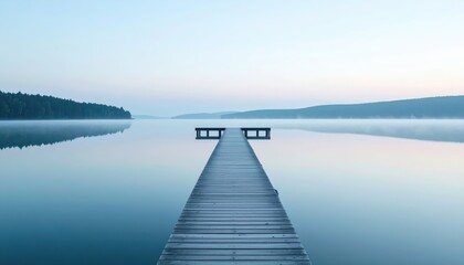 Serene long wooden dock extending over calm reflective lake with misty horizon and distant tree line du early morning peaceful scenery for relaxation and nature
