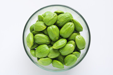 Top view of a clear glass bowl filled with fresh petai or pete, also known as stinky beans, isolated on a clean white background.