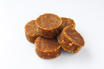 A pile of solid, dark brown palm sugar discs (gula jawa or gula merah), a traditional sweetener used in a variety of desserts, beverages, and savory dishes.