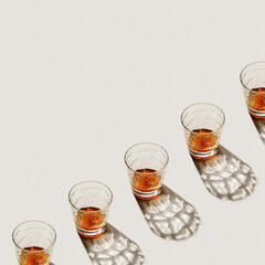 Crystal Glasses with drink at row, beautiful shadow at sunlight on beige textured background, minimal trend, aesthetic photo shiny glass, sun glare, strong alcohol drink concept, summer, copyspace