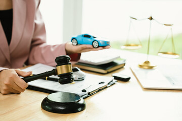 A judge’s gavel, justice scales, and toy car symbolize law, judgment, accident claims, traffic...