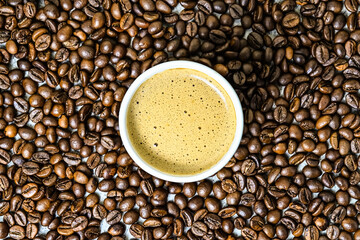 Top view of hot cappucino in the ceramic mug or glass with coffee beans on the background. scattered. high angle, above, close up. copy space, empty, free, negative, design, text. 