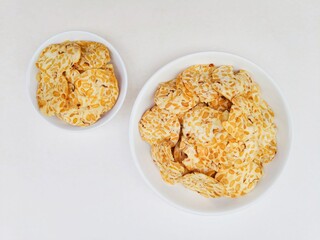 Tempeh chips in a white plate on a white background. Top of view. 