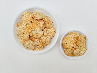 Tempeh chips in a white plate on a white background. Top of view. 