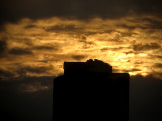 Obraz premium Skyscraper Rooftop Silhouette with Golden Cloud Crown — Sunset Macro on West Lake in Hanoi, Vietnam