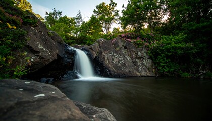 Fototapeta premium Cascading serenity a hidden waterfall nestled amidst lush greenery and weathered rocks offering a