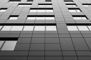 Modern high-rise building exterior with sleek dark gray tiled facade and multiple rectangular creating an urban architectural design