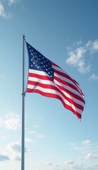 Fototapeta premium A view of the american flag waving gently in the wind against a bright blue sky with light clouds