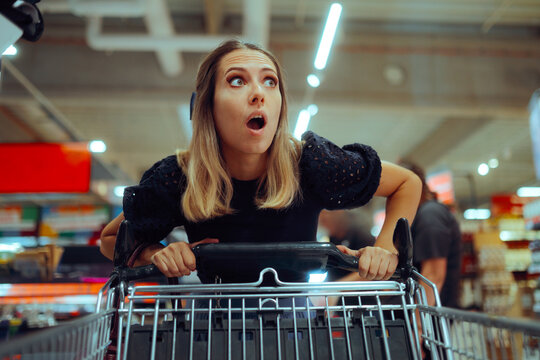 Funny Shopper Shocked by the Small Prices and Best offers. Amazed woman pushing her cart in a grocery store checking the promotions 