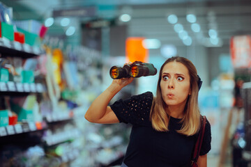 Woman with Binoculars Hunting for the Best Deals in Supermarket. Shopper exploring a big store...