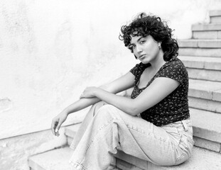 Young woman sitting on concrete steps, contemplating in monochrome