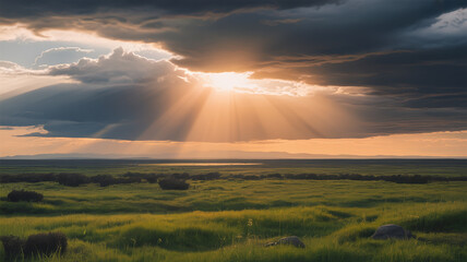 Sun rays pierce through the clouds over a green field, creating a dramatic and serene landscape at sunset with a beautiful horizon