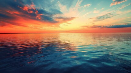 Obraz premium A breathtaking sunset over a calm sea. The sky explodes with vibrant colors, transitioning from fiery orange and red near the horizon to deep blues and turquoise higher up. 