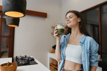 Young woman enjoying a nutritious green smoothie in a modern kitchen, embracing a healthy lifestyle...