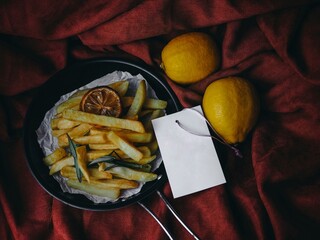 French fries with lemon on brown fabric in dark tone with copy space.