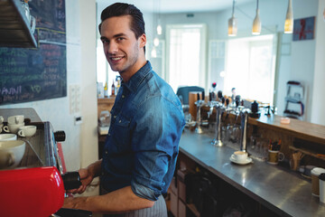 Barista operating red espresso machine, loading portafilter on counter under menu board at cafe