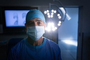 Overhead surgical lamp is glowing in operating room while monitor is displaying patient scans © wavebreak3