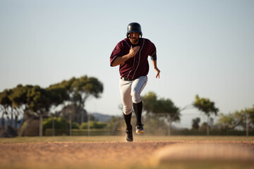Dust is kicking up from dirt path beneath racing baseball cleat on infield near outfield fence