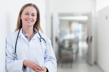 Mid adult female doctor standing in hospital corridor with stethoscope and lab coat, copy space
