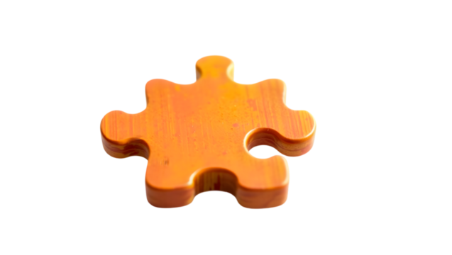Close up of a single orange puzzle piece isolated against a black background in studio shot