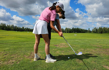 Instructor guides student in perfecting golf swing on sunny day