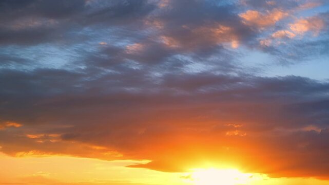 A sunset timelapse captures golden light breaking through dark clouds, painting the sky in fiery orange and soft blue tones, reflecting the shifting beauty of evening weather in nature&rsquo;s cycle.
