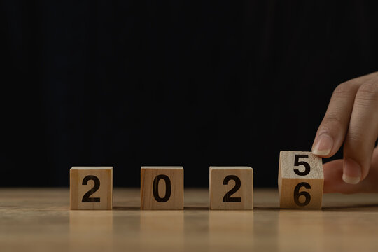 Hand Adjusts Wooden Block with Number Five to Complete Year Transition from 2025 to 2026 Against Dark Background for New Year Celebration - Powered by Adobe