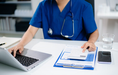 Healthcare costs and fees concept.Hand of smart doctor used a calculator and smartphone, tablet for...