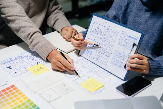 UX UI design team building mobile app wireframes and color palettes with real people, digital mockups, and teamwork in a tech office setting