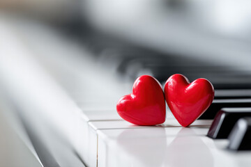 Close-up of two red hearts resting on piano keyboard, romantic music theme