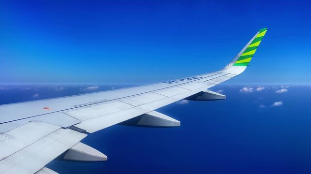 an airplane flys over blue ocean and horizon, starboard side view through the window,