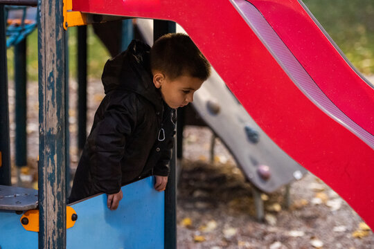Curious child exploring playground slide in autumn