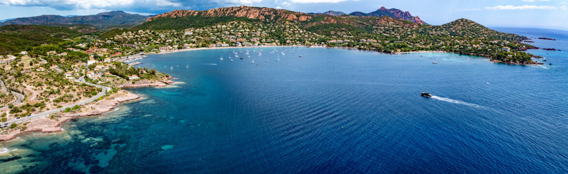 wide angle aerial landscape view of French Riviera coastline along Agay Bay in Saint-Rapha&euml;l with Plage d'Agay and Plage de La Baumette, boats anchored in bay, wooded hilly landscape in background