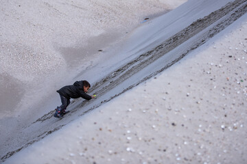 Child playing on a steep sandy slope at the beach