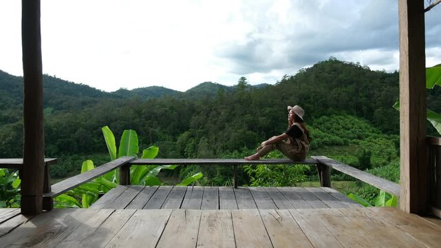 A woman sitting on wooden terrace and looking at a mountain view