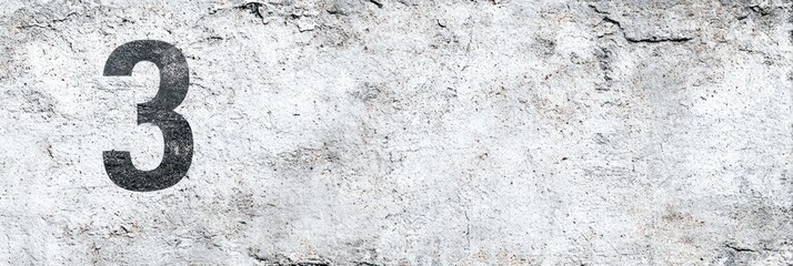 Number three displayed on a weathered, gray stone or concrete surface