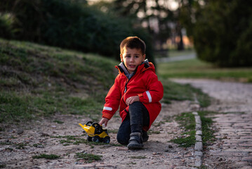 Sad child playing with toy truck in park during sunset
