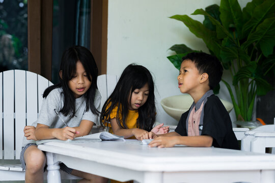 Children sitting around table, having discussion at home - Powered by Adobe