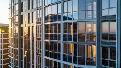Modern apartment building with glass facade at sunset 
