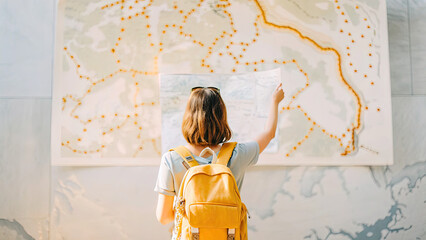 Woman with yellow backpack views map concept. Traveler exploring a map with a yellow backpack in urban setting.