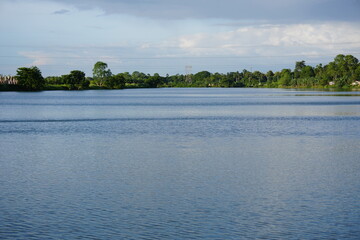 A body of water of a large lake, with trees and foliage lining the distant shore