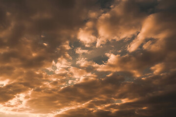 Obraz premium Dramatic golden and orange clouds illuminated by sunset light creating a fiery sky spectacle