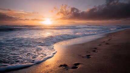 Footprints leading into the serene ocean at sunrise