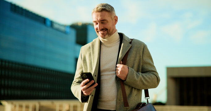 Phone, smile and business man in city for travel, check schedule or update with urban planner. Outdoor, mobile or mature employee on commute, communication and reading text for development approval - Powered by Adobe