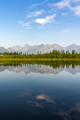 Mountain lake calm water with reflection, surrounded by forest, Kodar mountain range