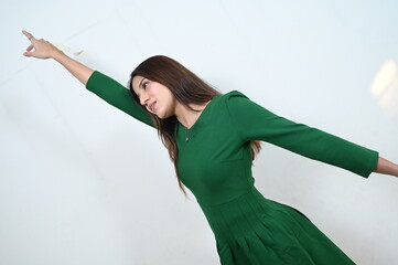 woman showing to the up. beautiful woman in green dress and white wall. finger shows to the up
