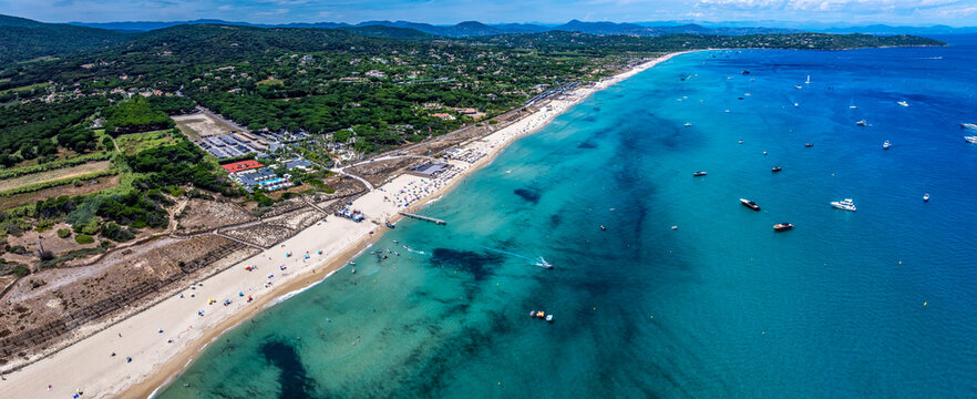 aerial landscape view along Pampelonne Beach to Saint-Tropez, located at coastline of Ramatuelle, C&ocirc;te d&rsquo;Azur, France, with people on the beach in water, green wooded hilly landscape in background
