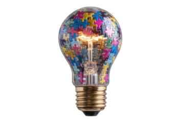 A glowing lightbulb filled with colorful jigsaw puzzle pieces