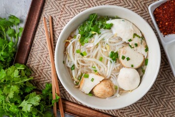 Clear noodle soup with thin rice noodles in ceramic bowl with chopsticks
